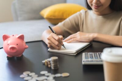 A lady sitting with a piggy bank, pen and paper illustrating no deposit home loans explained.
