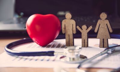 A red hear sits next to a wooden cut out of a family representing not for profit health insurance.