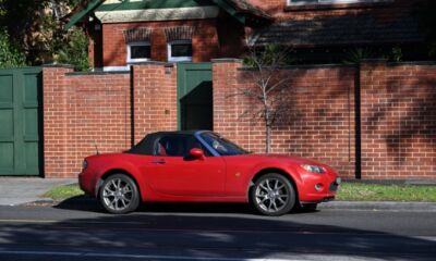 A red car in front of a house representing refinance home loan to buy car.
