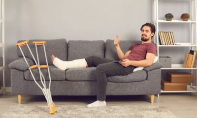 A man with a cast on his leg sits on the couch representing salary continuance insurance.