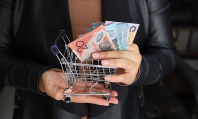 hand of a woman holding australian banknotes and a shopping cart
