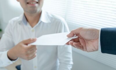 An employer hands an employee an envelope representing super on bonus.