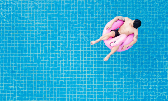 A man enjoying his swimming pool after contemplating how much does a pool cost?
