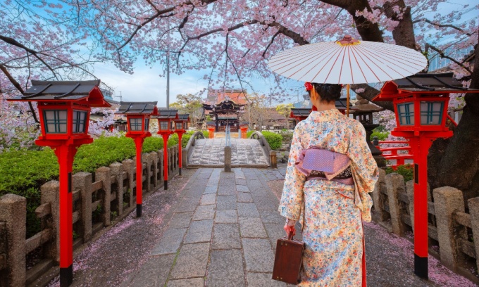 Women in kimono walking along stone path at Rokusonnō Shrine in Japan.