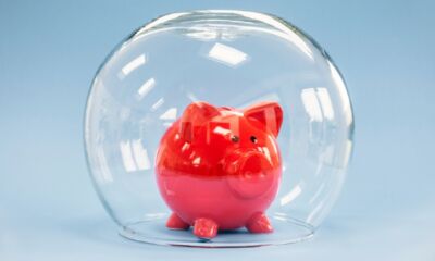 A red piggy bank under a glass fishbowl.