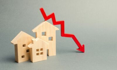 Some miniature wooden houses with a red arrow going down next to them representing what is negative equity?