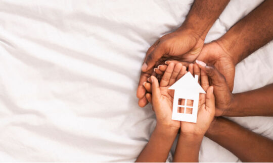 Black hands hold a small white house representing Aboriginal home loans.