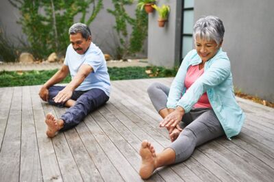 An older couple wearing exercise gear, stretching before physical exercise
