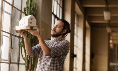 An architect holds up a miniature design of a house representing how much does an architect cost?