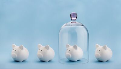four white piggy banks in a row, one has a glass bell jar over the top