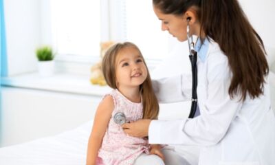 A doctor checks a child with a stethoscope representing private health insurance for kids.