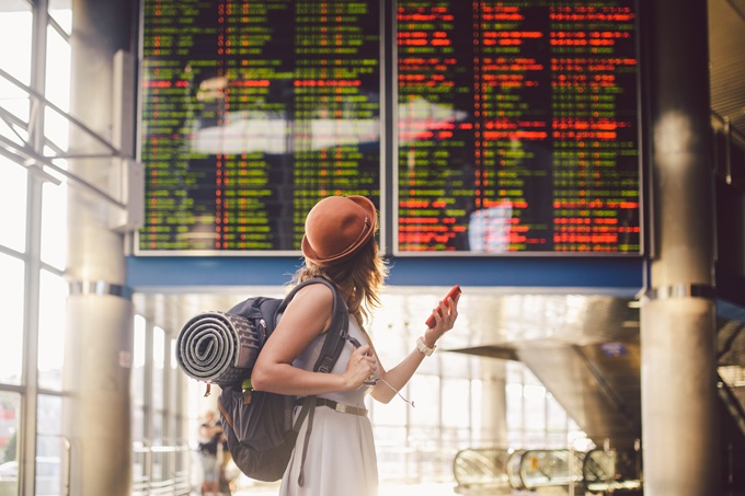 female traveller stands in front of departures screen