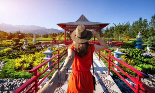 Woman running toward pagoda with a hat on